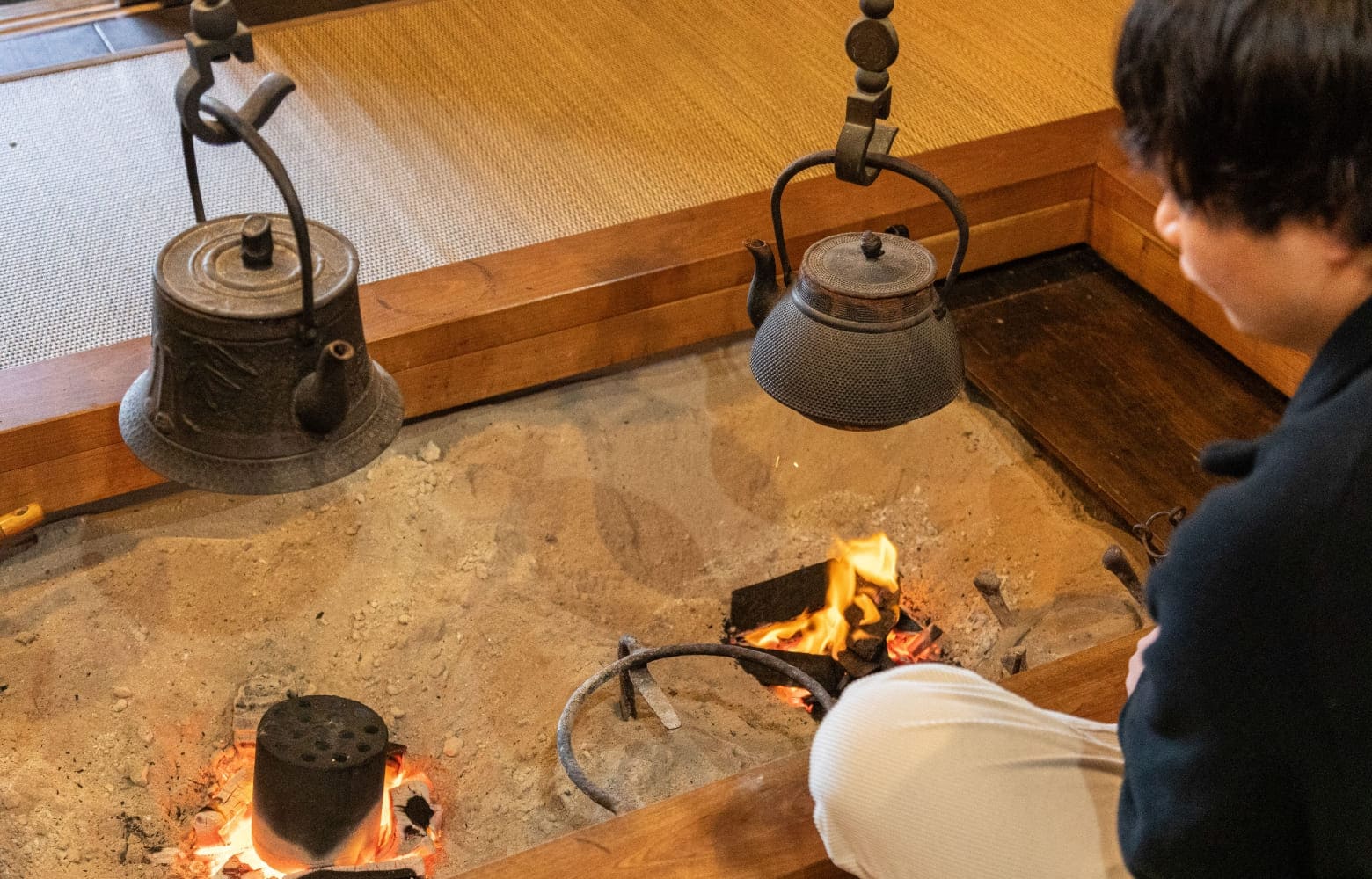 囲炉裏の火を見る男性