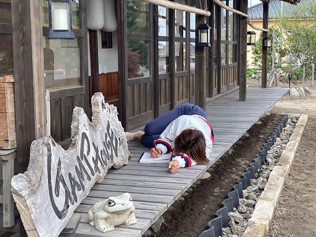 縁側でメモする女性